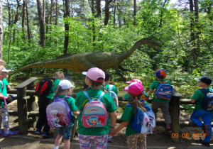 Dzieci oglądają postać dinozaura.